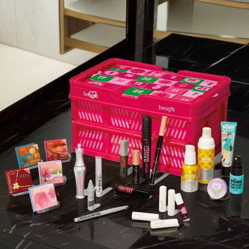 calendrier de l'avent maquillage benefit 2024 présenté dans un panier rose contenant 24 produits et accessoires maquillage
